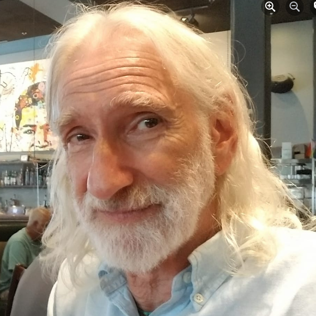 A white man with shoulder-length white hair and a white beard.
