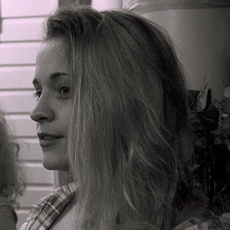 The photo is in black and white. A blonde woman in plaid looks to the left of the frame.
